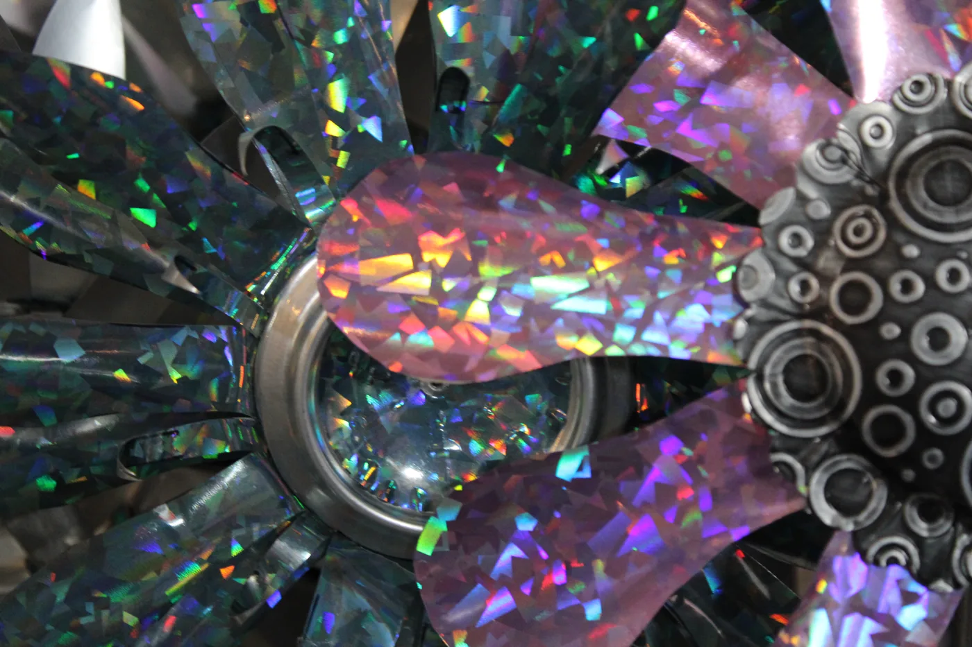 Close-up of a holographic pinwheel flower with rainbow reflections sparkling across its metallic petals