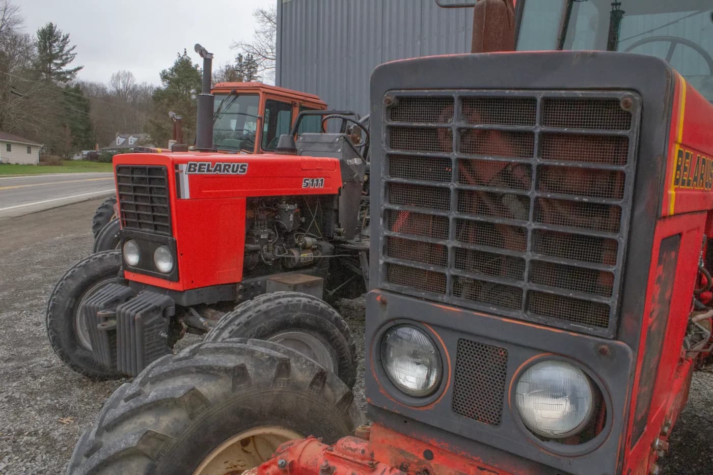 A lineup of bright red tractors beside a small-town road and houses