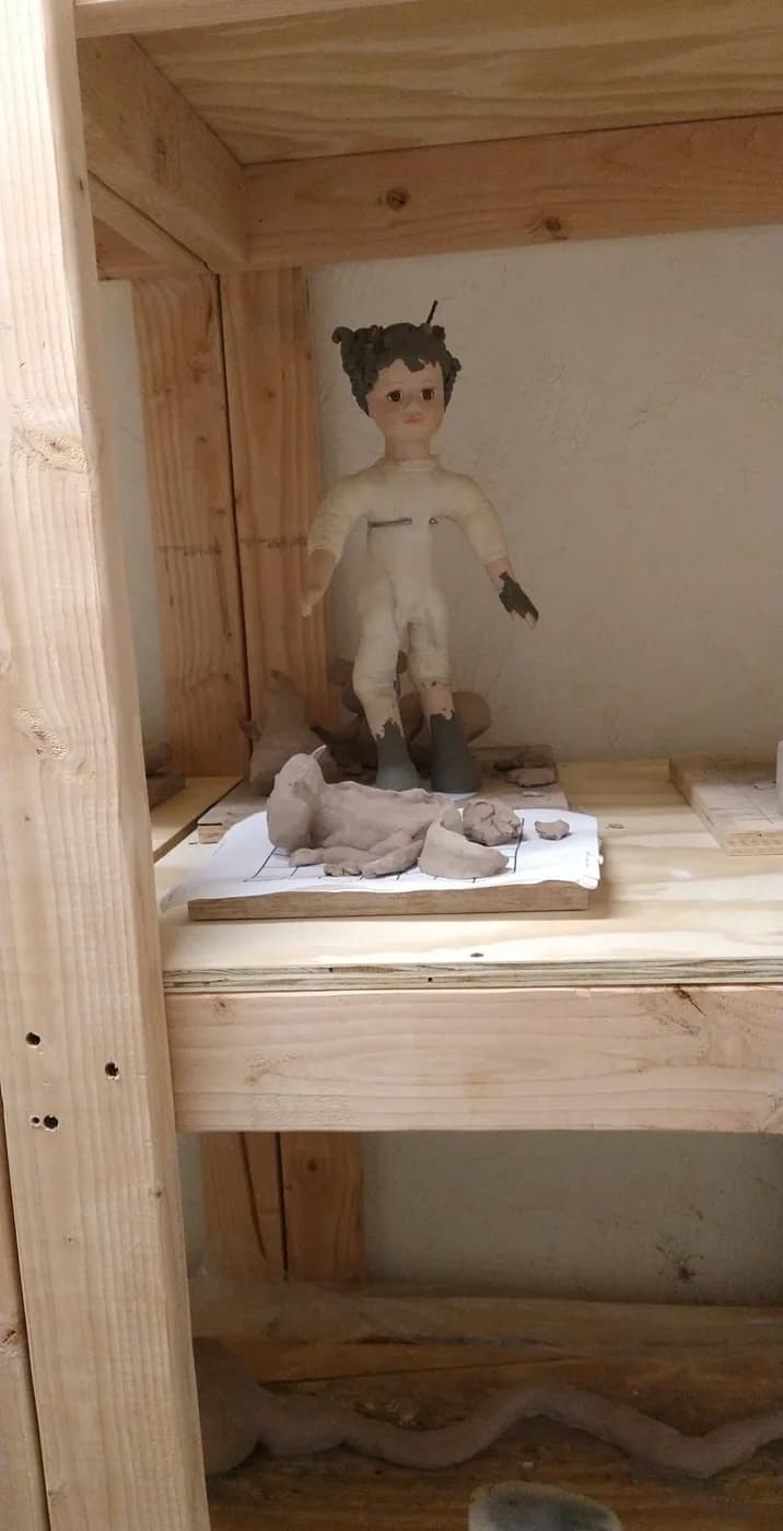 A doll figure in an orange jumpsuit standing on a shelf
