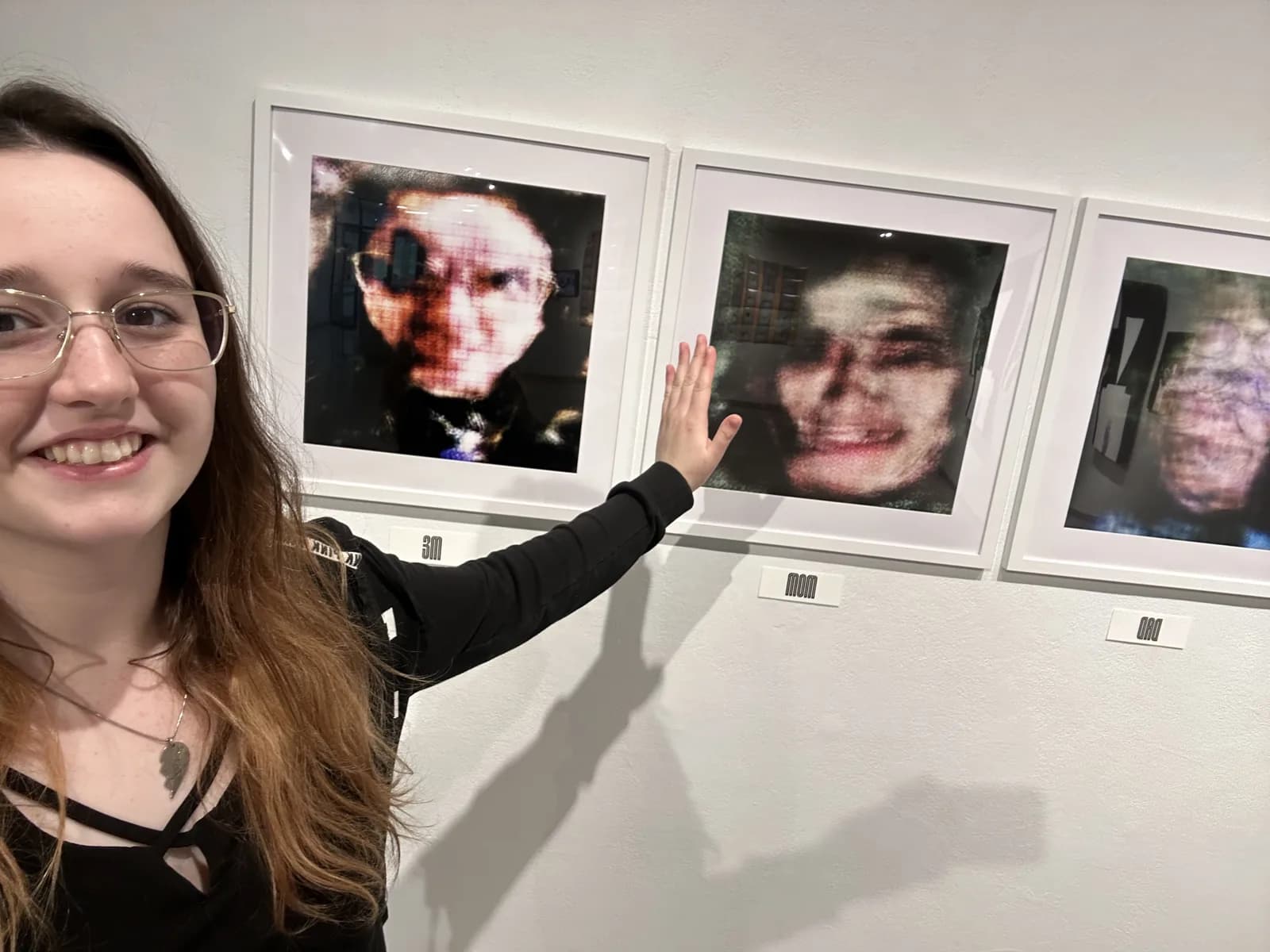 Pallas smiling beside her framed GAN portraits in the gallery